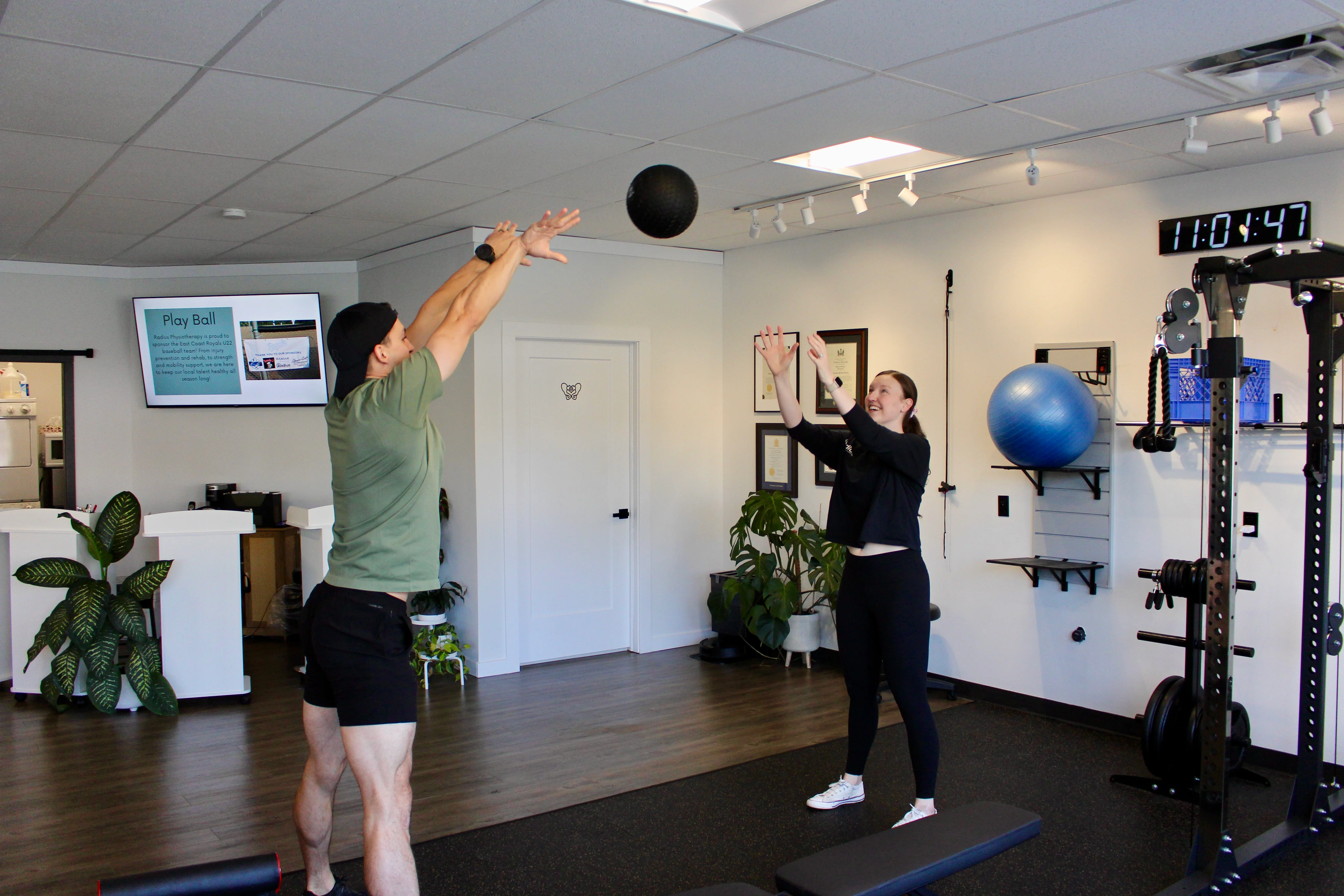 A Radius physiotherapist catching a medicine ball thrown by a patient in the clinic gym.