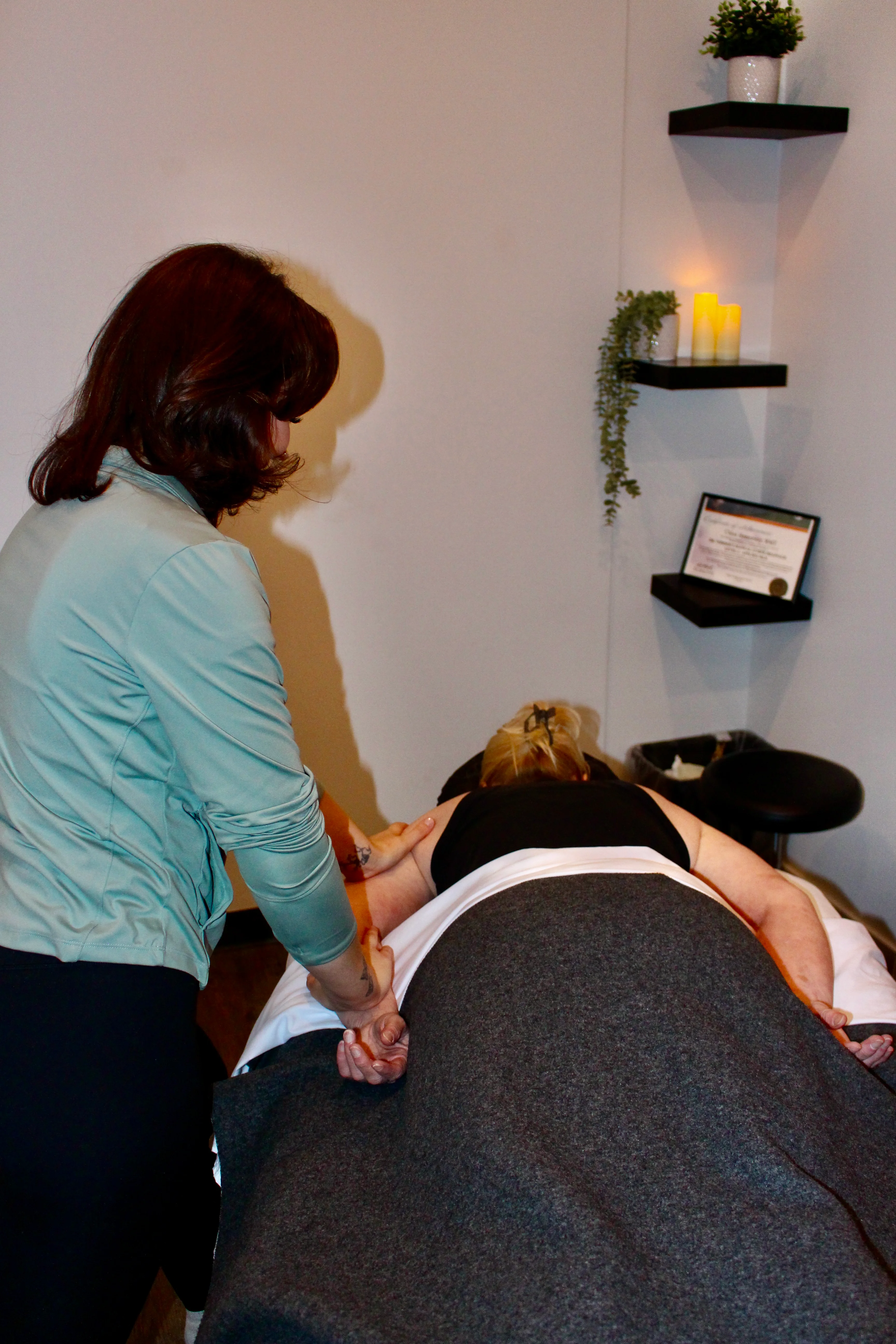 A Radius registered massage therapist working on the shoulder of a patient lying face down on a treatment table.
